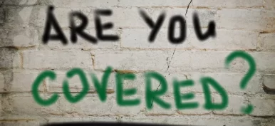 The words "Are You Covered" painted on a brick wall