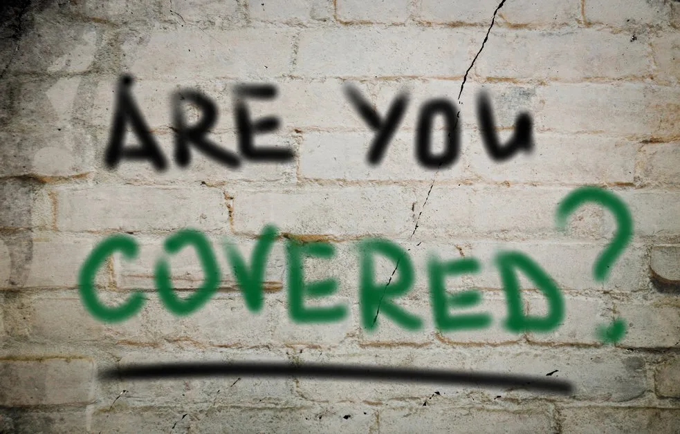 The words "Are You Covered" painted on a brick wall