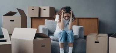 Tired european woman sitting among packed boxes. Hopeless young lady getting in trouble