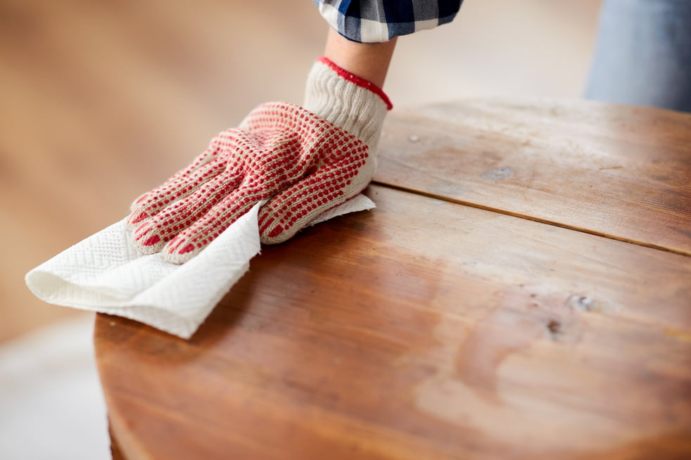 woman cleaning old table surface with paper tissue