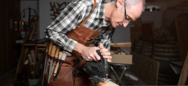 Carpenter is sawing a wood plank with electric jig saw machine in carpentry workshop. Workwood DIY concept