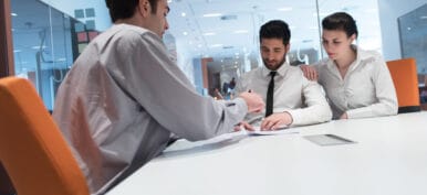 signing contract on partners back, young couple on business meeting with life insurance and bank loan agent at modern office interior