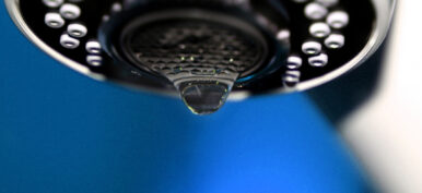 A macro of a white tap / faucet dripping.