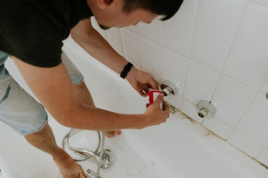 A young man wraps tow around the nut of a bathroom faucet.