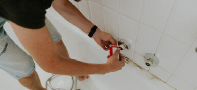 A young man wraps tow around the nut of a bathroom faucet.