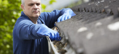 Man Clearing Leaves From Guttering Of House